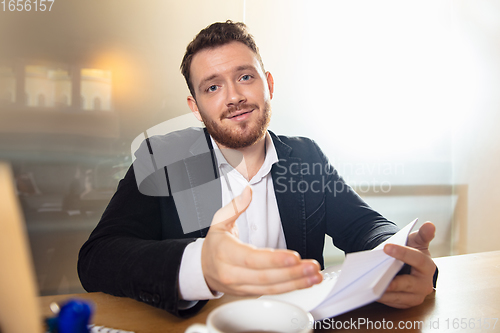 Image of Young man talking, working during videoconference with colleagues at home office