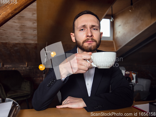 Image of Young man talking, working during videoconference with colleagues at home office