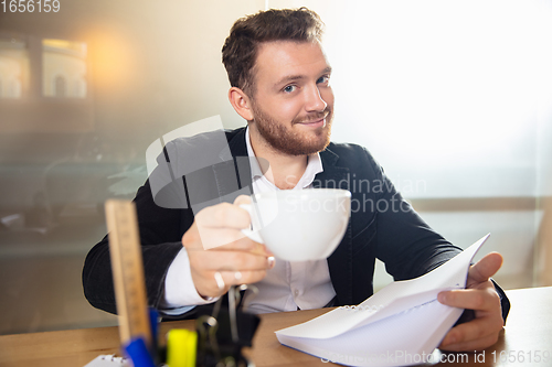 Image of Young man talking, working during videoconference with colleagues at home office