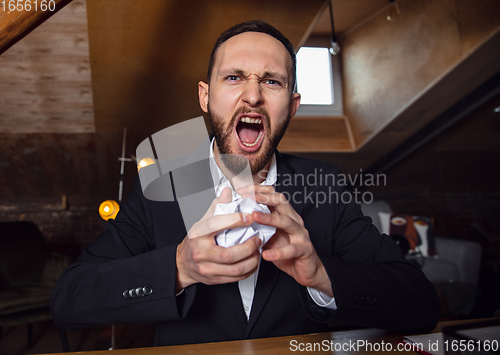 Image of Young man talking, working during videoconference with colleagues at home office