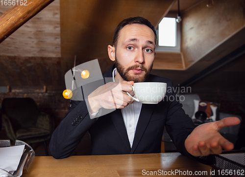 Image of Young man talking, working during videoconference with colleagues at home office