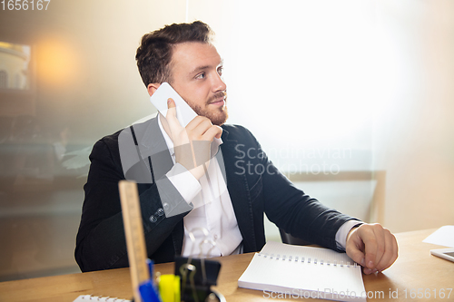 Image of Young man talking, working during videoconference with colleagues at home office