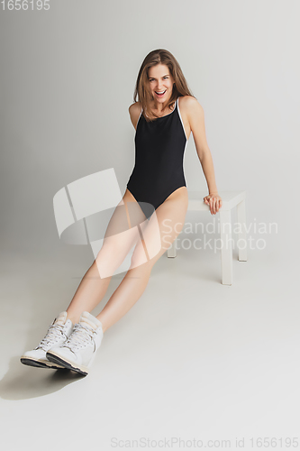 Image of Beautiful young woman\'s portrait isolated on grey studio background. Having fun, happy, full length