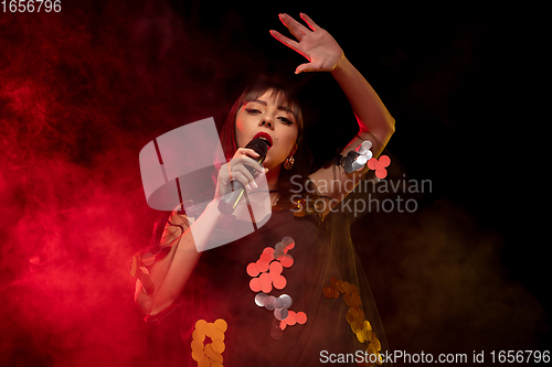 Image of Caucasian female singer portrait isolated on dark studio background in neon light