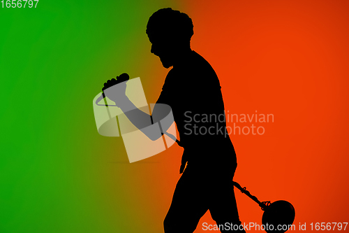 Image of Silhouette of young caucasian male singer isolated on green-orange gradient studio background in neon light