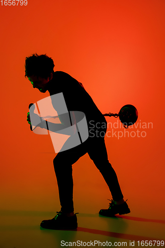 Image of Silhouette of young caucasian male singer isolated on orange gradient studio background in neon light