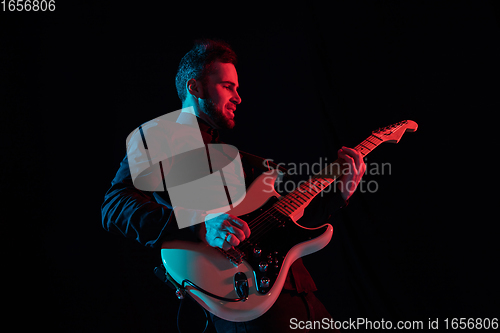 Image of Silhouette of young caucasian male guitarist isolated on blue-pink gradient studio background in neon light