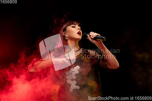 Image of Caucasian female singer portrait isolated on dark studio background in neon light