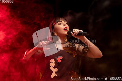 Image of Caucasian female singer portrait isolated on dark studio background in neon light