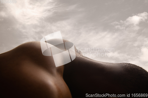 Image of Detailed texture of human skin. Close up shot of young african-american male body like landscape with the sky background