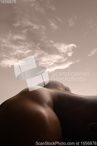 Image of Detailed texture of human skin. Close up shot of young african-american male body like landscape with the sky background