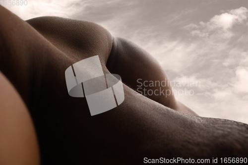 Image of Detailed texture of human skin. Close up shot of young african-american male body like landscape with the sky background