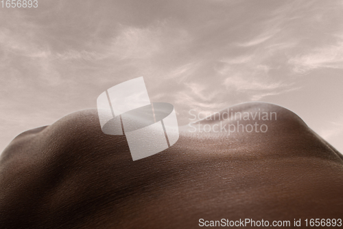 Image of Detailed texture of human skin. Close up shot of young african-american male body like landscape with the sky background