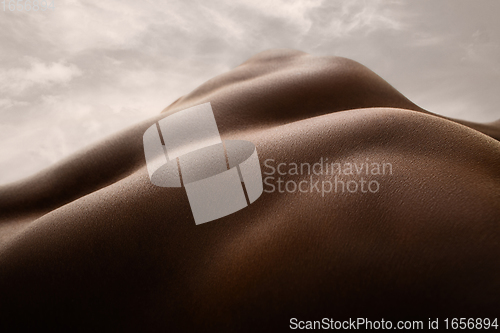 Image of Detailed texture of human skin. Close up shot of young african-american male body like landscape with the sky background