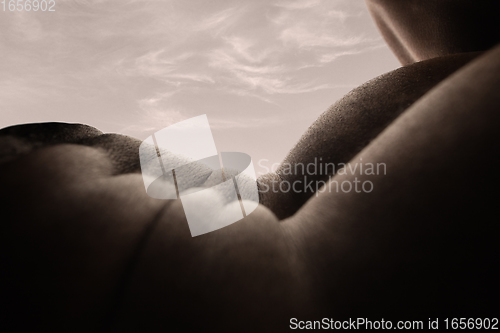 Image of Detailed texture of human skin. Close up shot of young african-american male body like landscape with the sky background