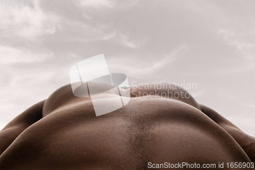 Image of Detailed texture of human skin. Close up shot of young african-american male body like landscape with the sky background