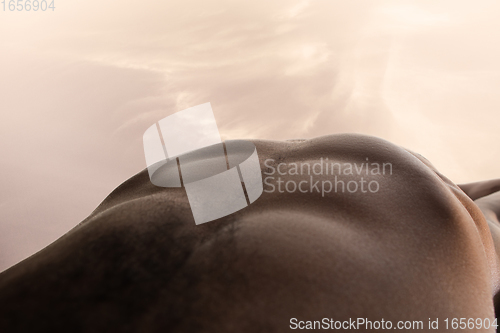 Image of Detailed texture of human skin. Close up shot of young african-american male body like landscape with the sky background