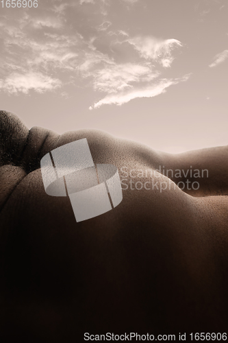 Image of Detailed texture of human skin. Close up shot of young african-american male body like landscape with the sky background