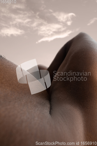 Image of Detailed texture of human skin. Close up shot of young african-american male body like landscape with the sky background