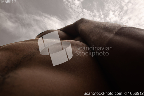 Image of Detailed texture of human skin. Close up shot of young african-american male body like landscape with the sky background