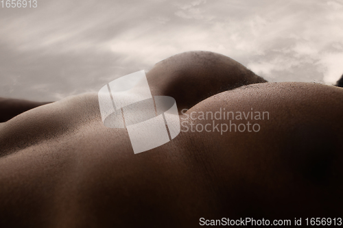 Image of Detailed texture of human skin. Close up shot of young african-american male body like landscape with the sky background