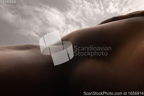 Image of Detailed texture of human skin. Close up shot of young african-american male body like landscape with the sky background