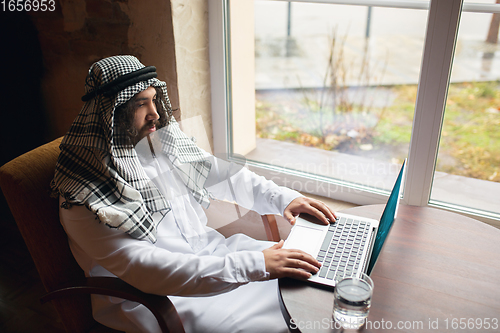 Image of Arabian businessman working in office, business centre using devicesm gadgets. Lifestyle