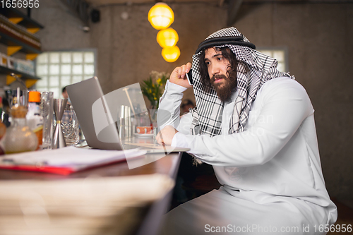 Image of Arabian businessman working in office, business centre using devicesm gadgets. Lifestyle