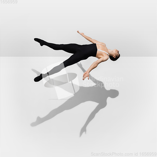 Image of Beautiful young male athlete practicing on white studio background with shadows in jump, air flying