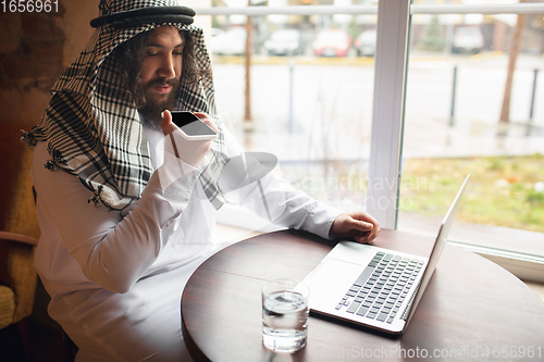 Image of Arabian businessman working in office, business centre using devicesm gadgets. Lifestyle