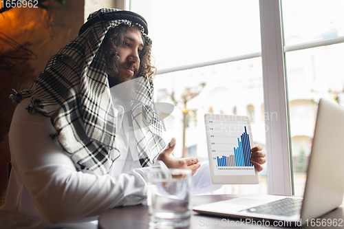 Image of Arabian businessman working in office, business centre using devicesm gadgets. Lifestyle