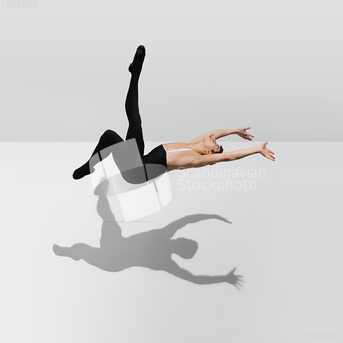 Image of Beautiful young male athlete practicing on white studio background with shadows in jump, air flying