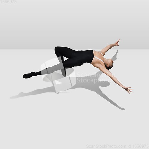 Image of Beautiful young male athlete practicing on white studio background with shadows in jump, air flying