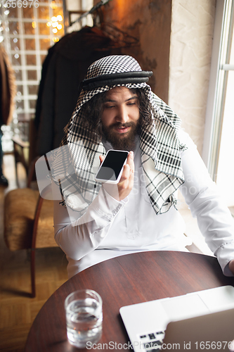 Image of Arabian businessman working in office, business centre using devicesm gadgets. Lifestyle