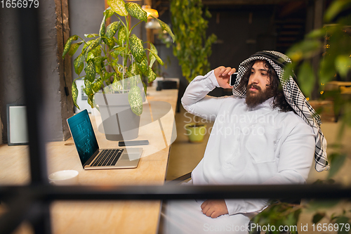Image of Arabian businessman working in office, business centre using devicesm gadgets. Lifestyle