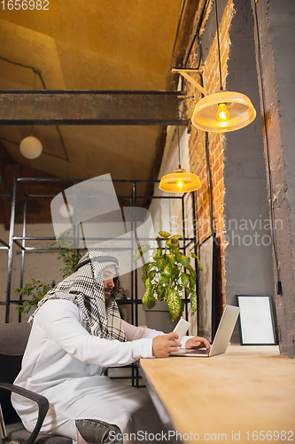 Image of Arabian businessman working in office, business centre using devicesm gadgets. Lifestyle