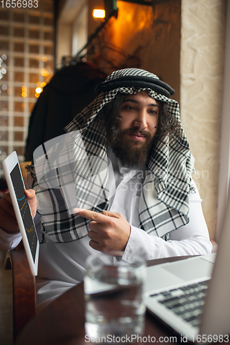 Image of Arabian businessman working in office, business centre using devicesm gadgets. Lifestyle