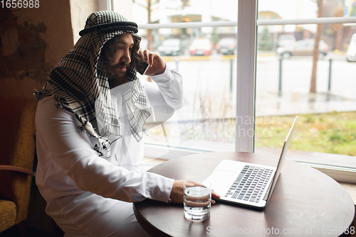 Image of Arabian businessman working in office, business centre using devicesm gadgets. Lifestyle