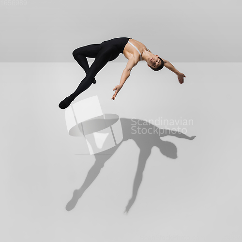 Image of Beautiful young male athlete practicing on white studio background with shadows in jump, air flying