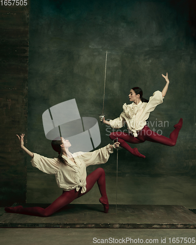 Image of Two young female ballet dancers like duelists with swords. Ballet and contemporary choreography concept. Creative art photo.