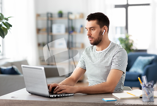 Image of man with laptop and earphones at home office