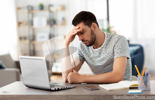 Image of stressed man with laptop working at home office