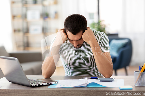 Image of man with files and calculator works at home office