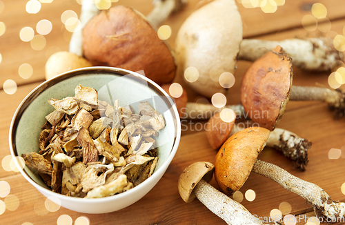 Image of dried mushrooms in bowl on wooden background