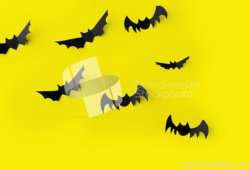 Image of flock of black paper bats over yellow background