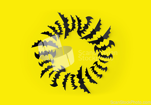 Image of flock of black paper bats over yellow background