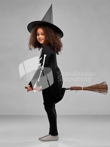 Image of girl in black witch hat with broom on halloween