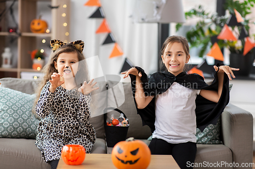 Image of girls in halloween costumes with candies at home