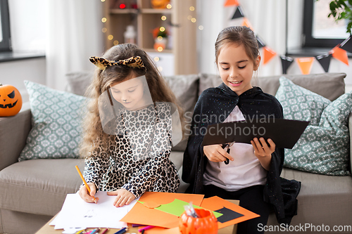 Image of girls in halloween costumes doing crafts at home