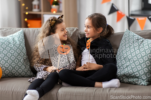 Image of girls in halloween costumes with pumpkins at home